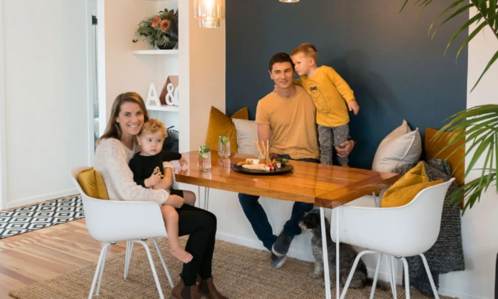 A smiling family of four sits around a wooden dining table-new zealand travel guide