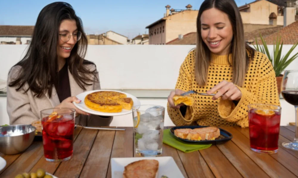 Two women smile while enjoying a meal on a rooftop-mexico city travel guide