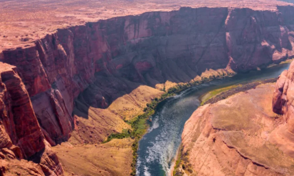 Aerial view of the Colorado River winding through the steep, red cliffs of the Grand Canyon-places to visit in arizona