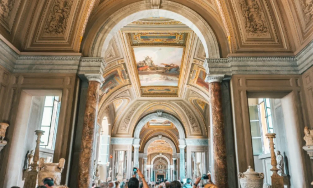 A grand museum corridor with ornate arches and a painted ceiling-places to visit in italy