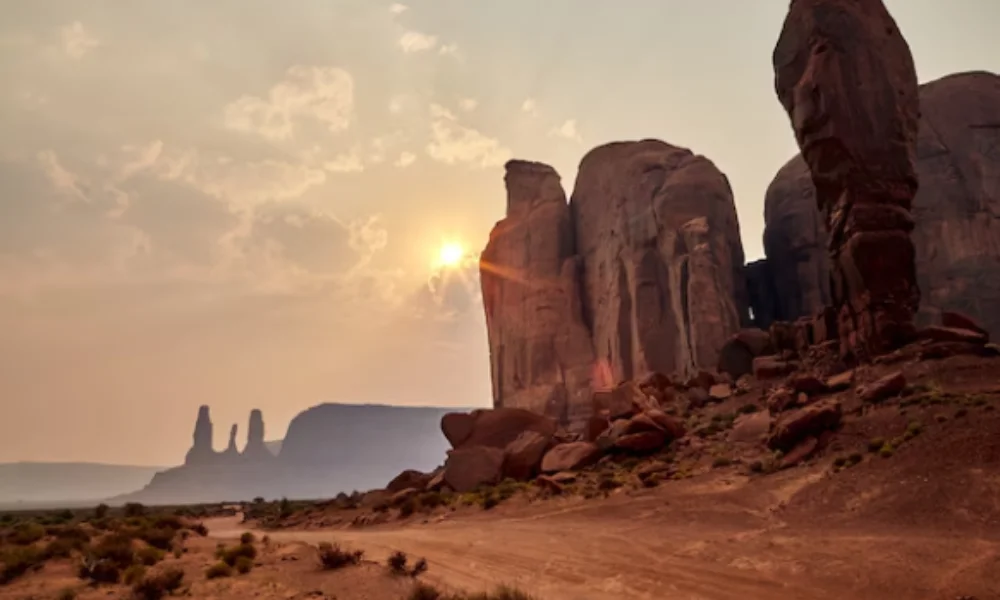 Sunset view of Monument Valley with towering red rock formations and a rugged dirt path-places to visit in arizona