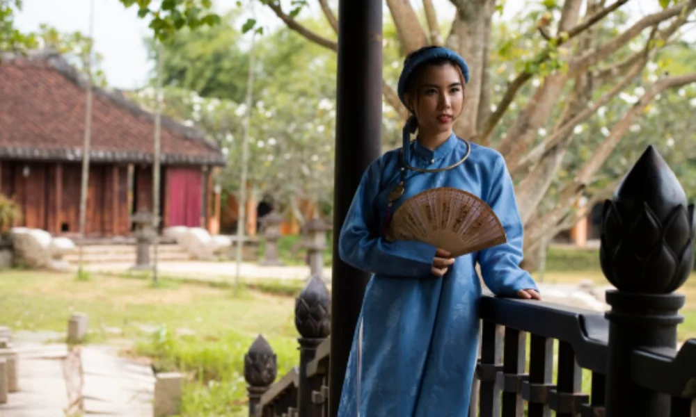 A woman in a traditional blue dress holds a decorative fan-countries in north asia