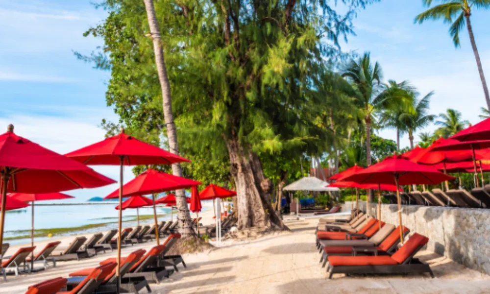 Sunny beach scene with red umbrellas, brown lounge chairs on sandy beach-travel destinations in cuba