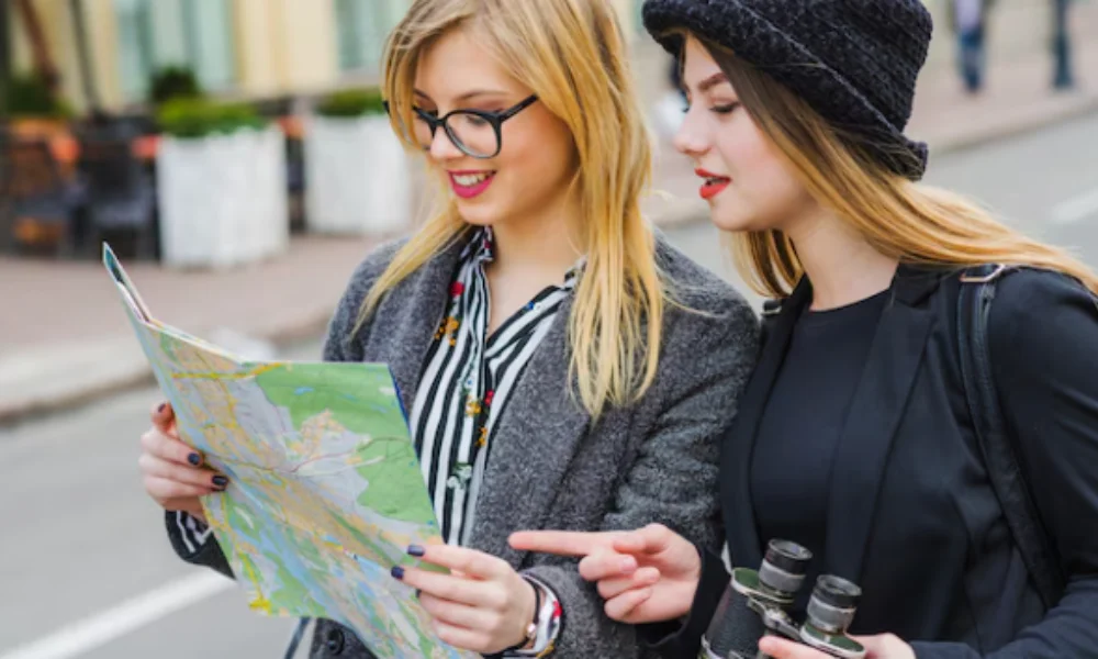 Two women stand on a city street studying a map-Manhattan Travel Guide Map