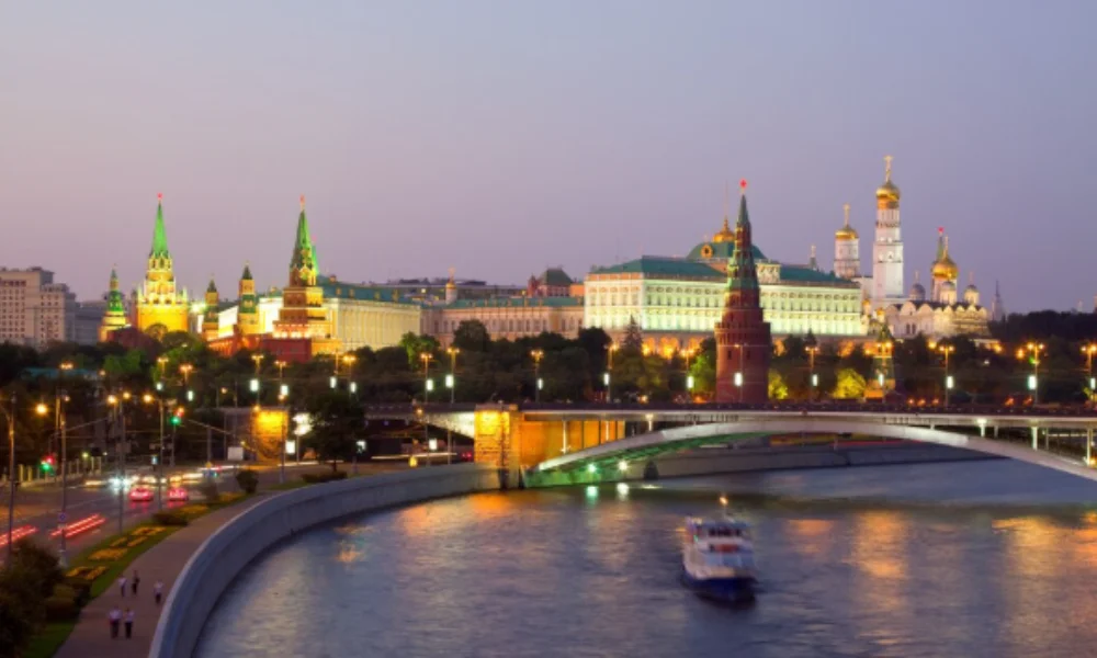 Twilight view of Moscow Kremlin skyline with illuminated towers and golden domes reflected in the river below