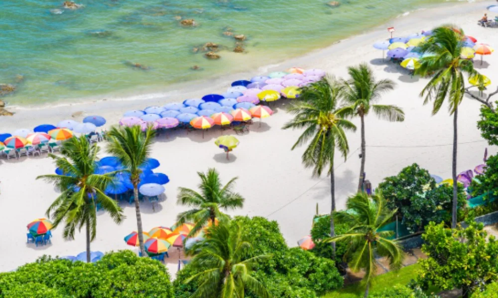 Aerial view of a vibrant beach scene with rows of colorful umbrellas and lounge chairs
