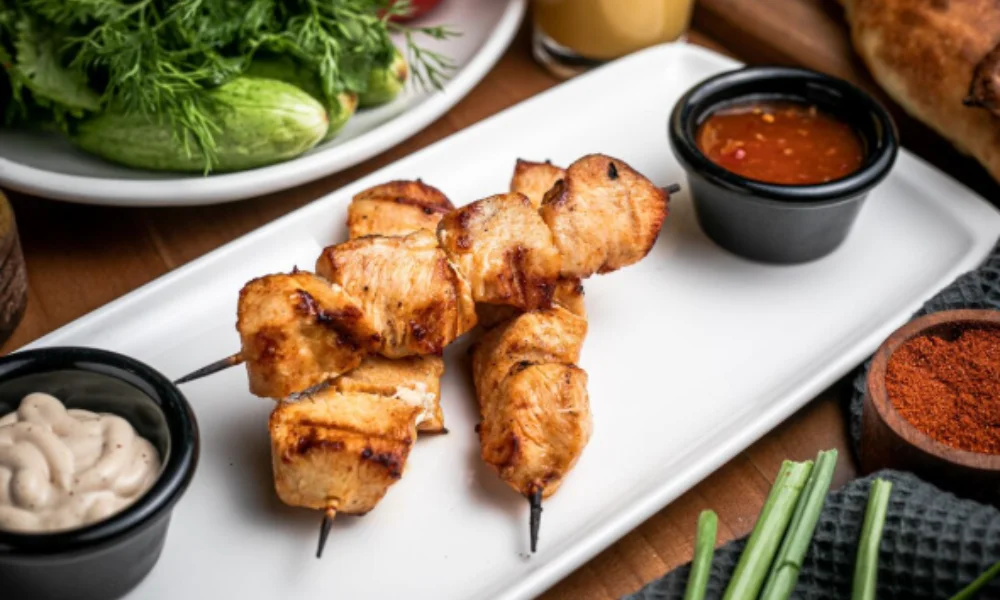 Grilled chicken skewers on a white plate with creamy and spicy dipping sauces-family easy dinner recipes
