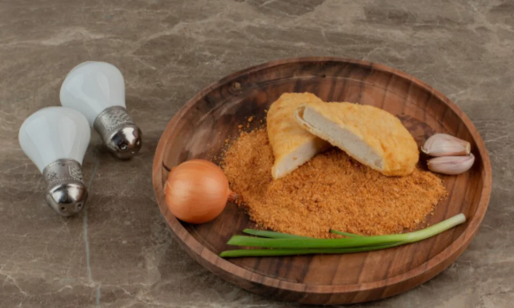 A wooden plate with a sliced breaded patty on golden breadcrumbs-easy chicken parmesan recipe