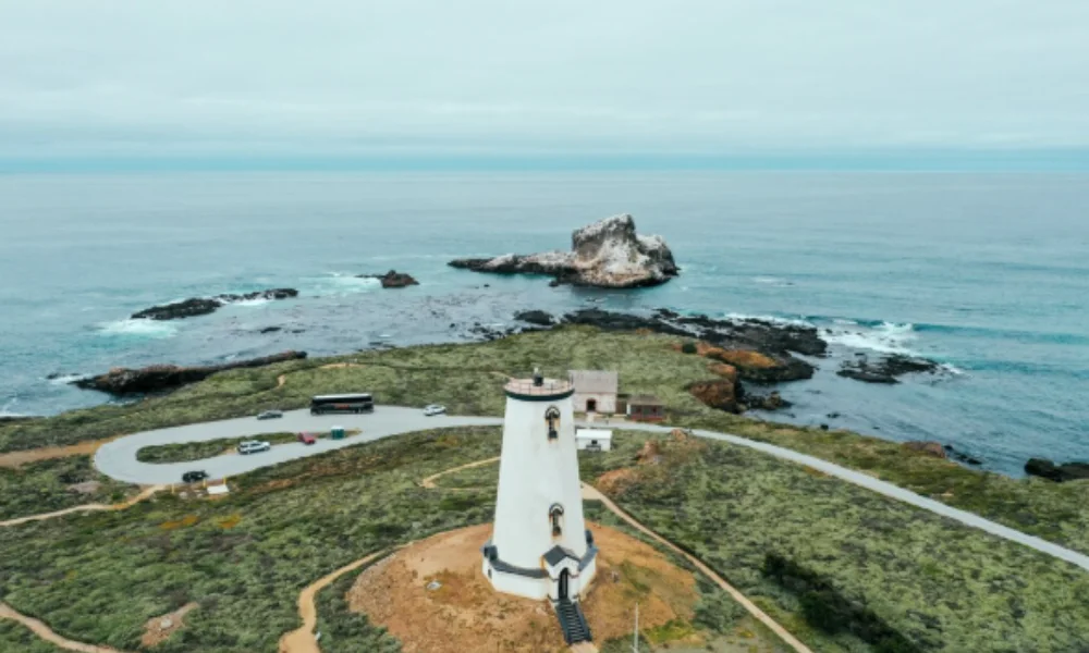 A tall white lighthouse stands on a grassy coastal landscape-places to visit on the east coast