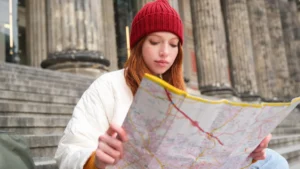 A woman sits on steps, studying a map, with a thoughtful expression