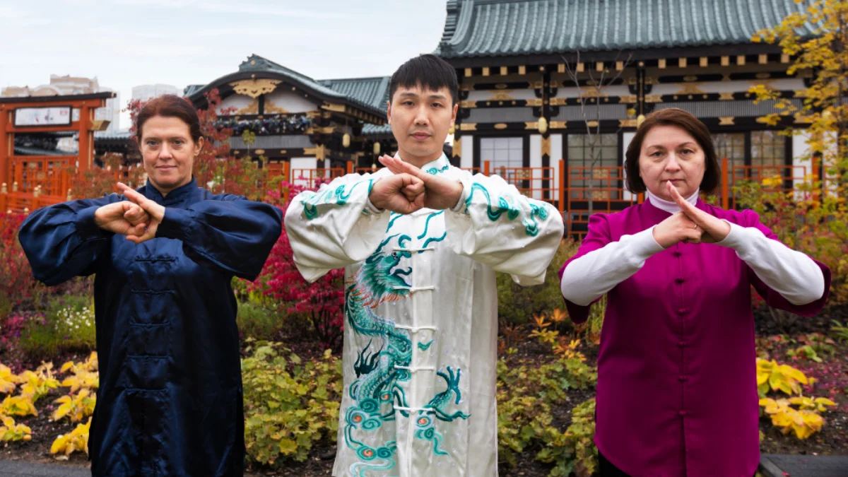 Three people stand in front of a traditional Asian building