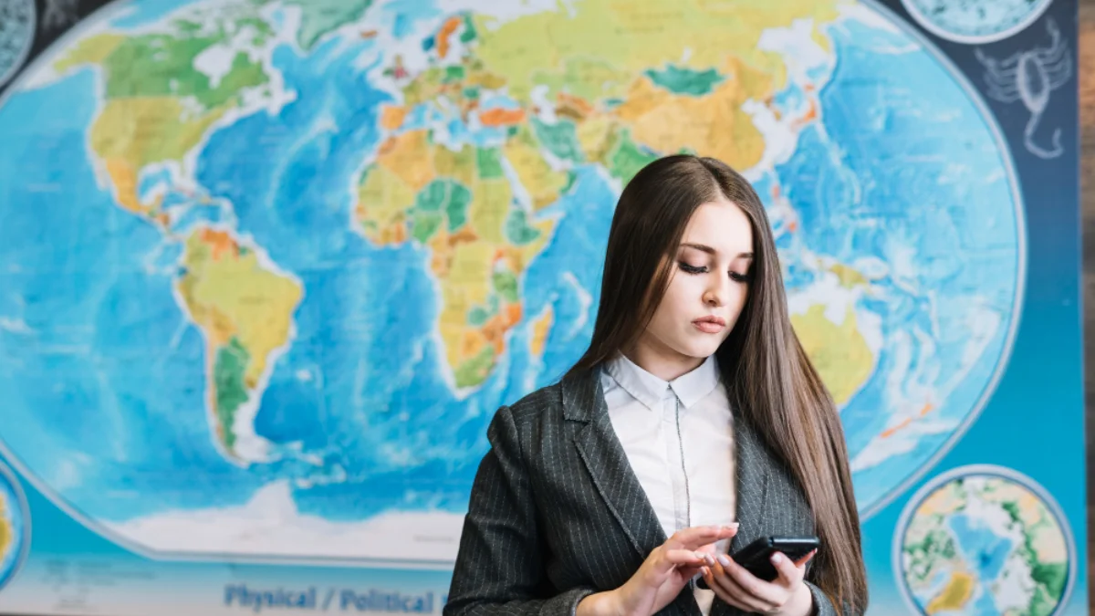 A young woman in a business suit looks focused as she uses her smartphone