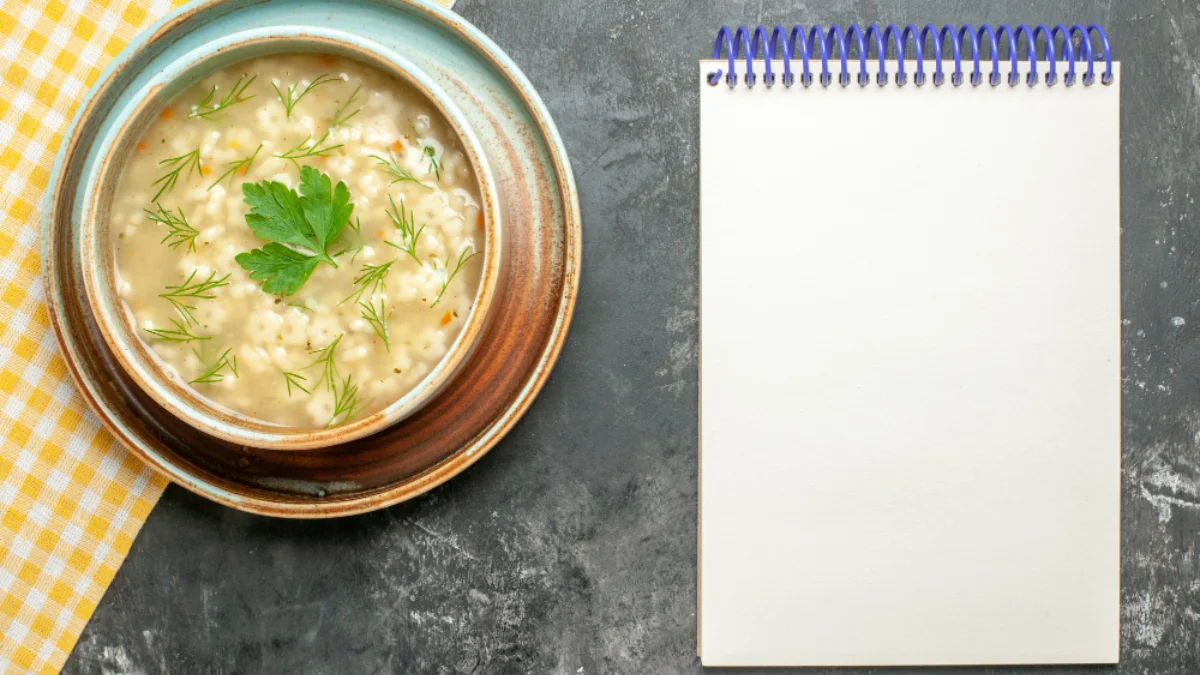 A bowl of creamy soup garnished with herbs sits on a patterned napkin