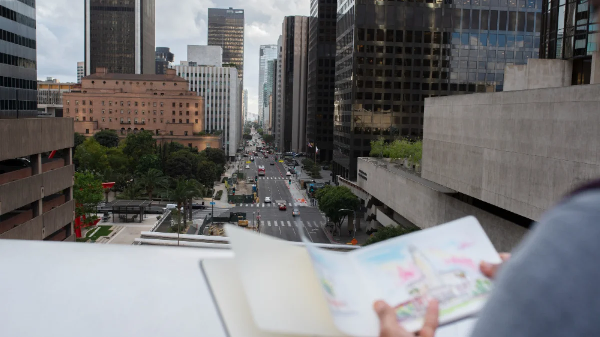 Aerial view of a bustling city street lined with tall buildings under a cloudy sky
