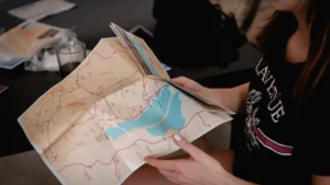 A person sits at a table, examining a detailed map
