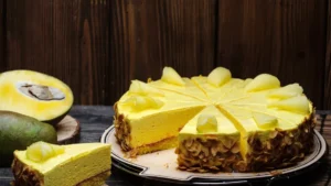 A vibrant yellow cake with almond flakes on the side, topped with sliced fruit pieces
