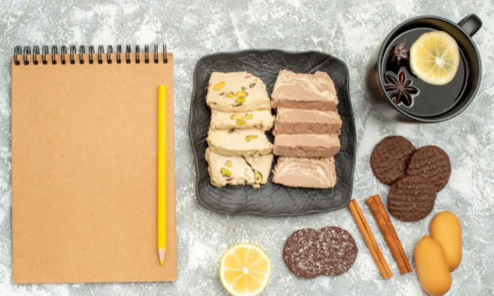 A notepad with a pencil is placed next to a plate of pistachio and chocolate halva-easy fudge recipes