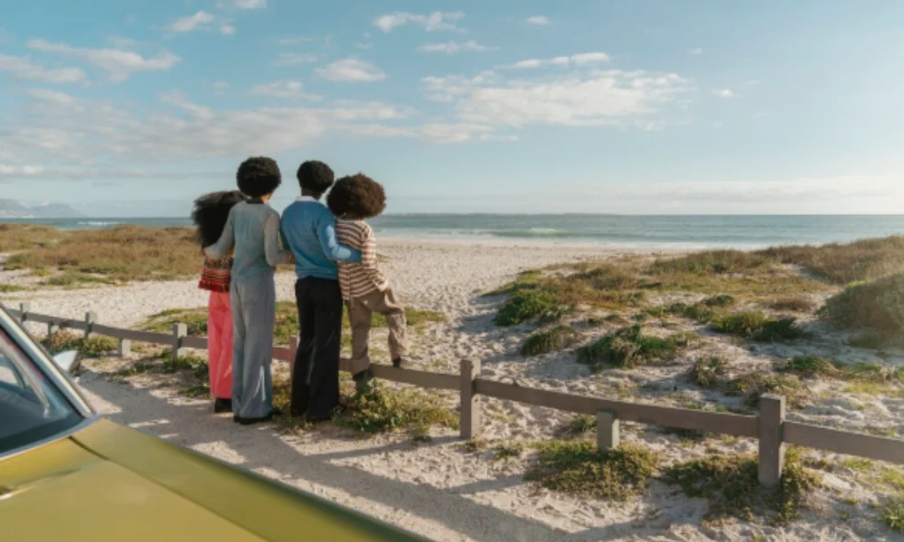 A family of four stands on a sandy beach, looking at the ocean under a bright blue sky-florida places to visit