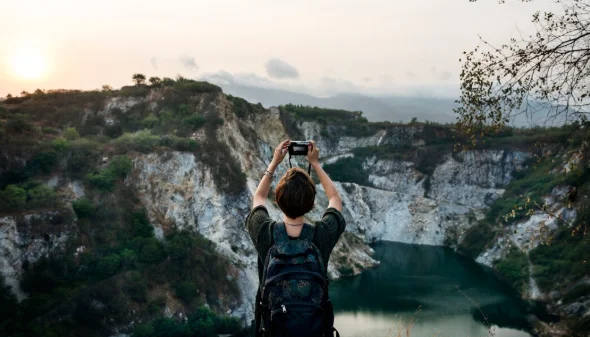 Person with backpack photographing a scenic view of a large canyon at sunrise-travel destinations in europe