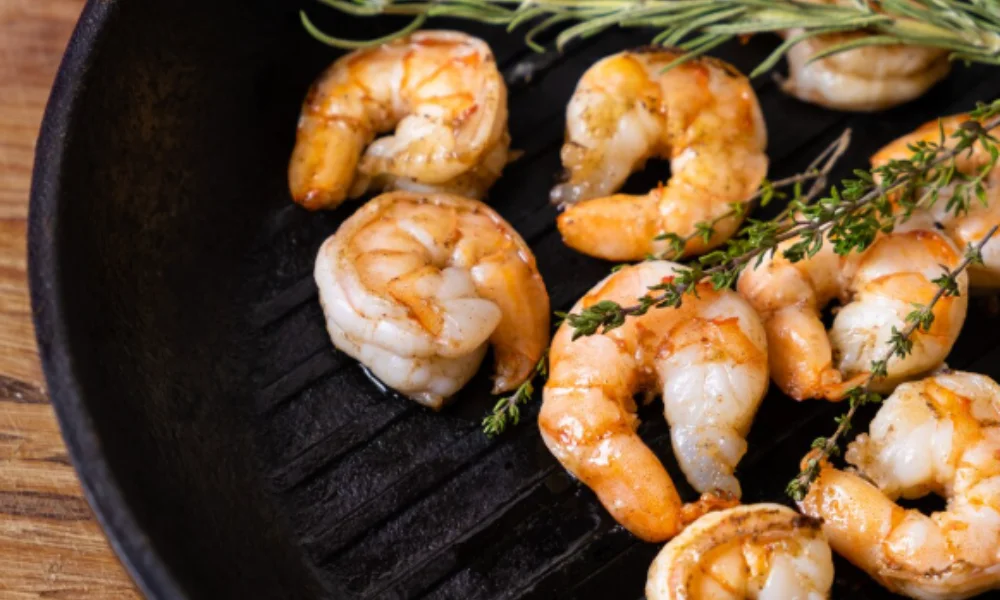 Grilled shrimp in a pan garnished with rosemary and thyme