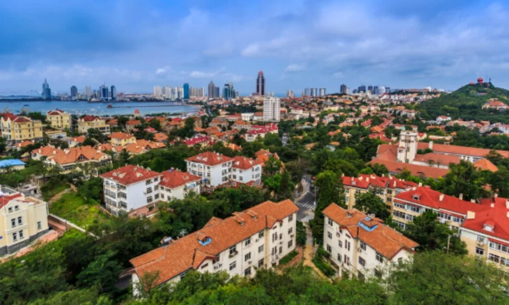 Aerial view of Qingdao, China showcasing red-roofed buildings amidst lush greenery