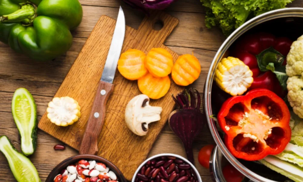 A vibrant assortment of fresh vegetables on a wooden tabletop includes sliced carrots, bell peppers-easy crockpot chilli recipe