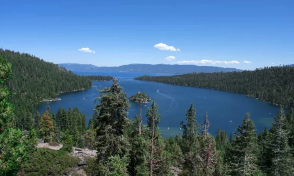 Scenic view of a deep blue lake surrounded by lush green forests under a clear blue sky with a few clouds-places to visit in washington state