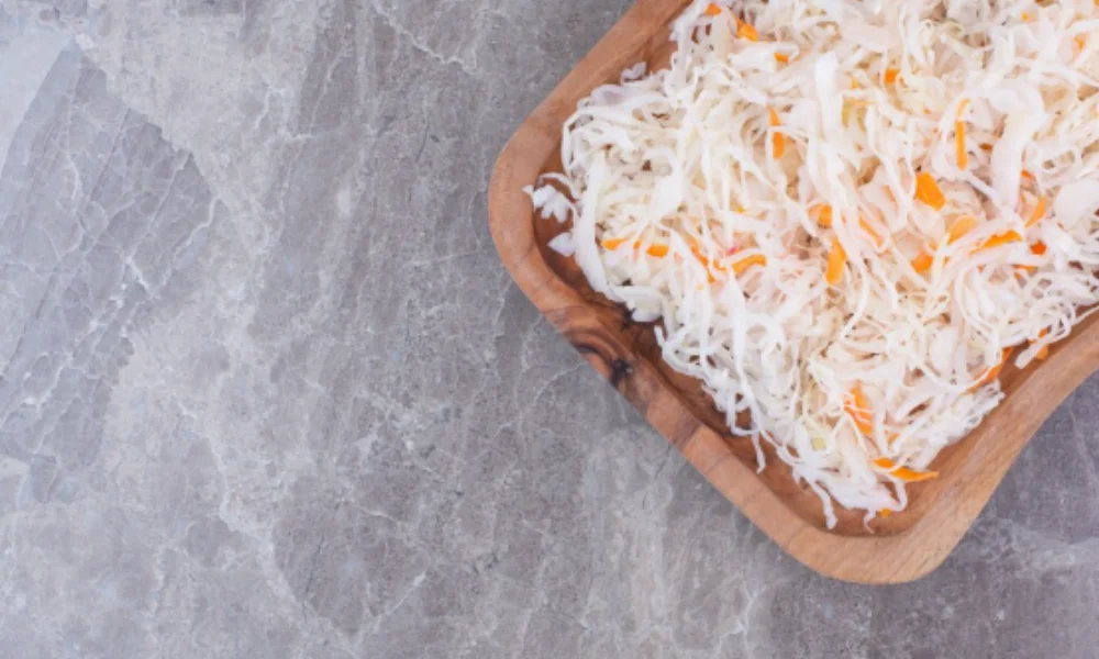 A wooden tray filled with shredded cabbage and carrots
