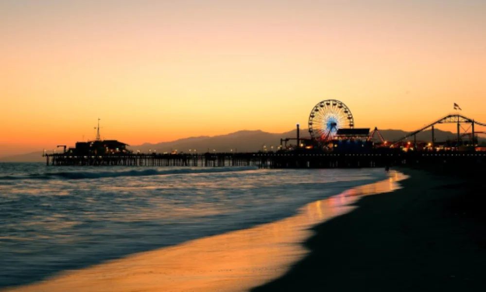 Sunset view of a beach with a pier extending into the ocean-places to go in the us