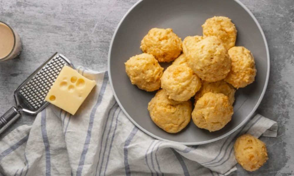 A bowl of round, golden cheese scones sits on a gray table-easy cheeseball recipes