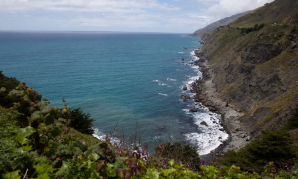 Rocky coastline with blue ocean waves and lush greenery in the foreground-tropical places to visit