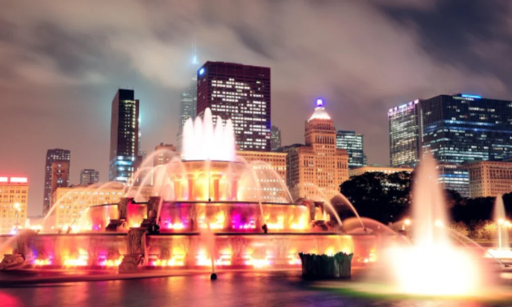 A vibrant night scene of a city fountain illuminated with colorful lights 