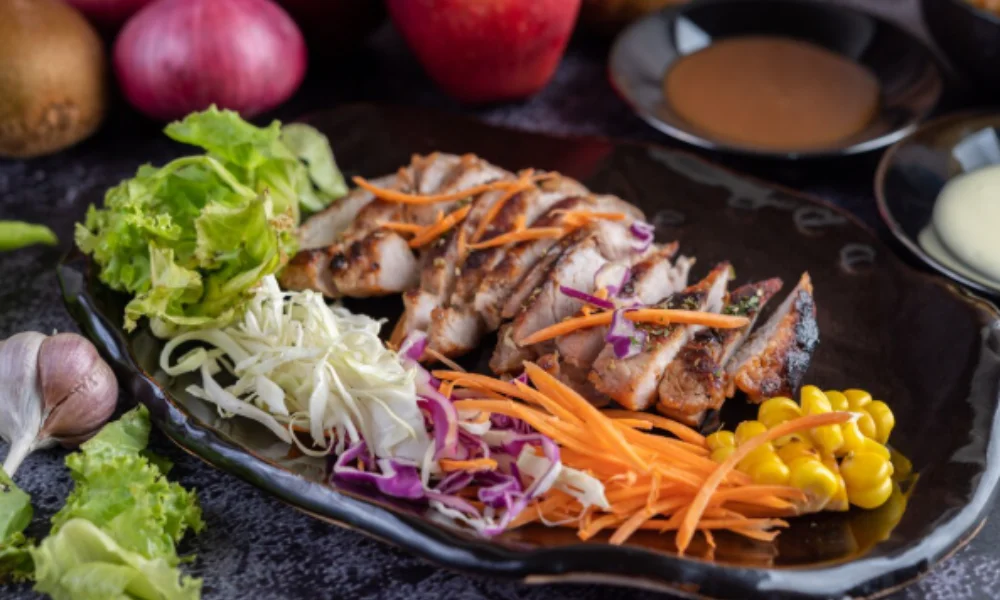 Grilled chicken slices with colorful cabbage, carrots, and corn on a dark plate-easy coleslaw recipe