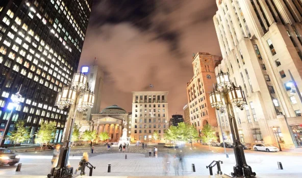 Nighttime cityscape with tall, illuminated buildings and vintage street lamps