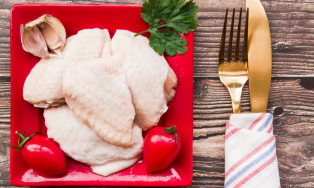Raw chicken wings on a red plate with garlic-easy chicken parmesan recipe