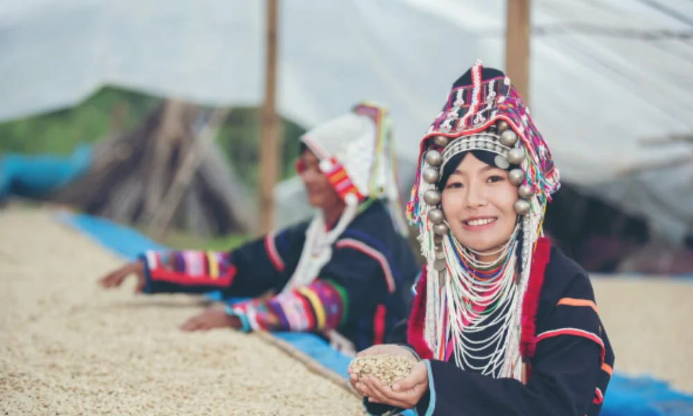 A woman in traditional, colorful attire with intricate headdress smiles while holding grains-places to visit in peru
