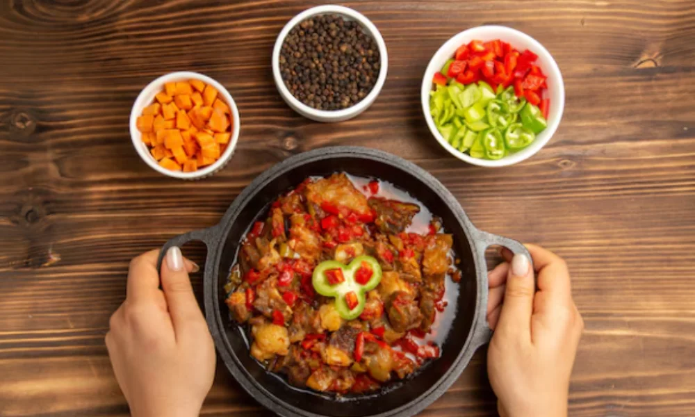 A person holds a black skillet filled with a colorful stew-easy crockpot chilli recipe