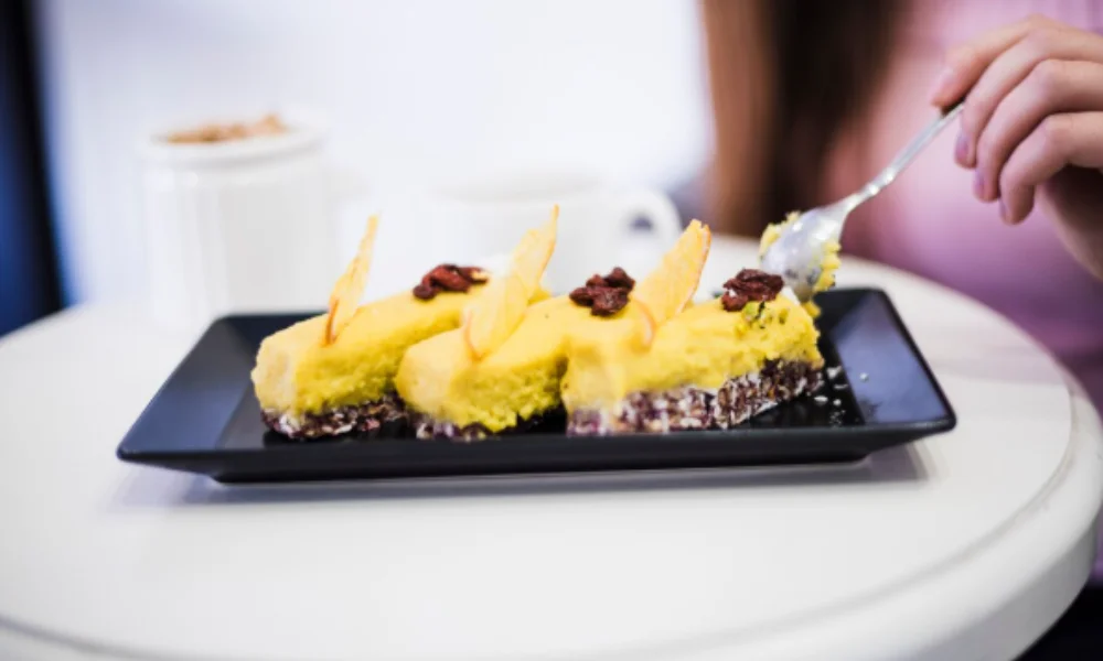 A person enjoys a slice of bright yellow cake on a black plate-easy pineapple upside down cake recipe
