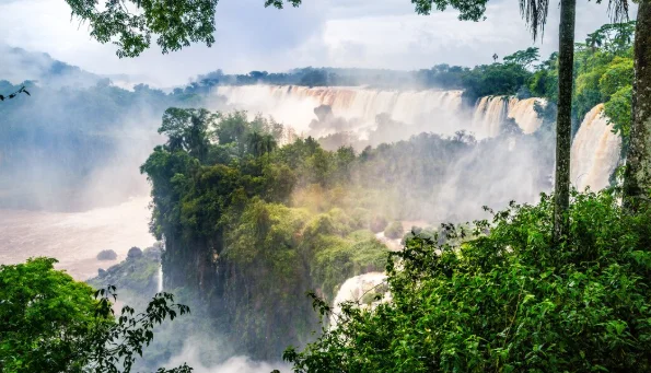 A vast, misty waterfall cascades over a lush, green rainforest-south america travel destinations