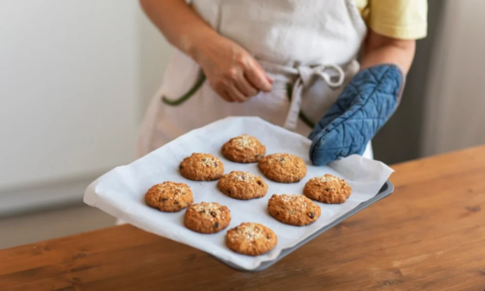 A person holds a tray of freshly baked cookies on parchment paper-easy banana muffin recipe