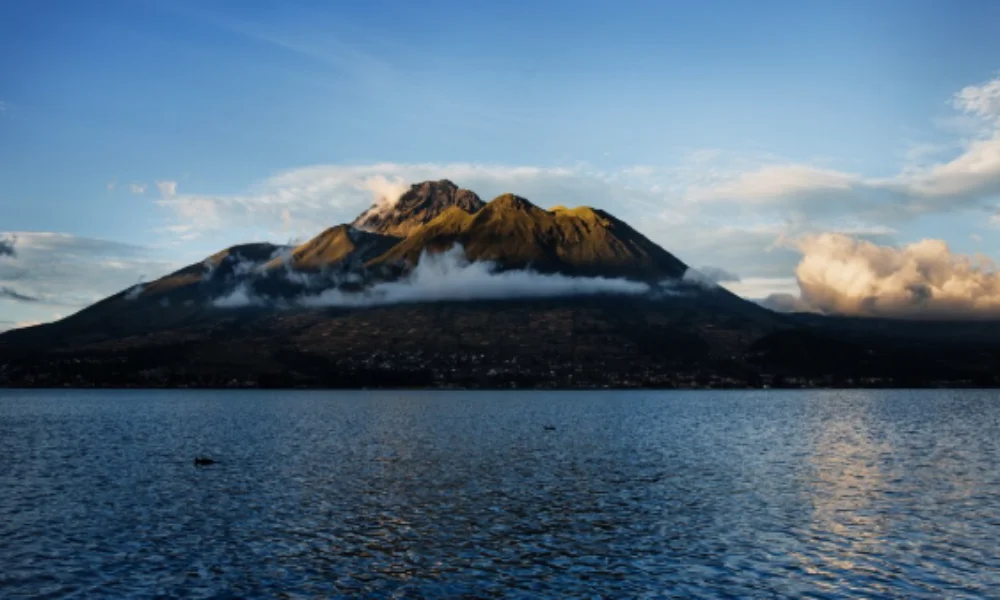 A tranquil lake reflects a majestic mountain under a clear blue sky