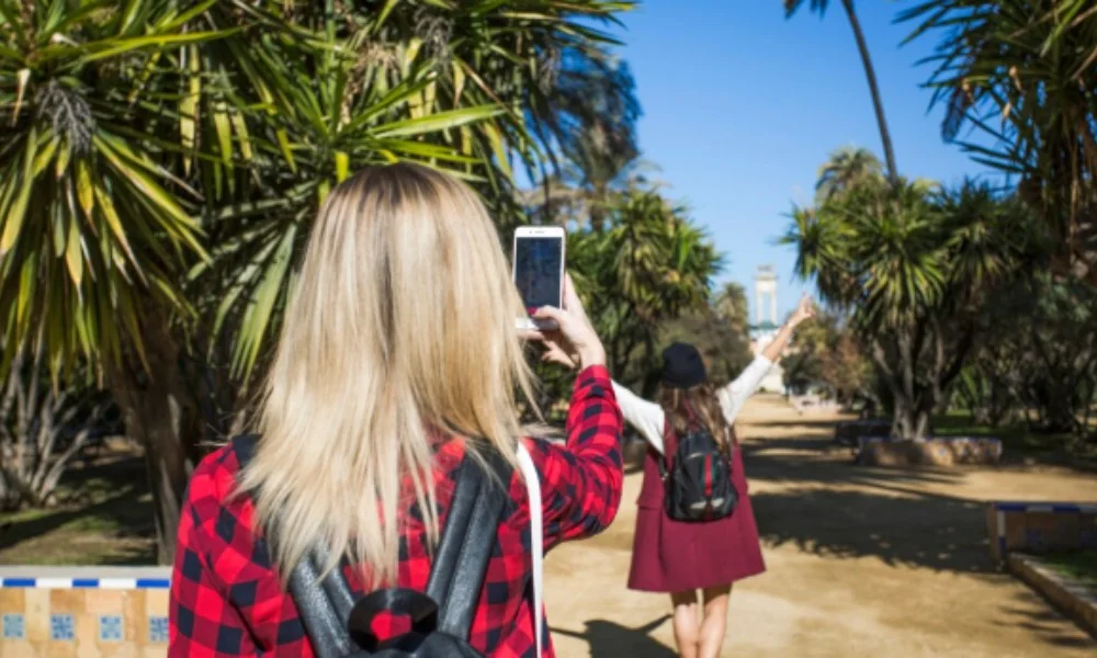 a girl in red shirt heaving a bag and phone in hand
