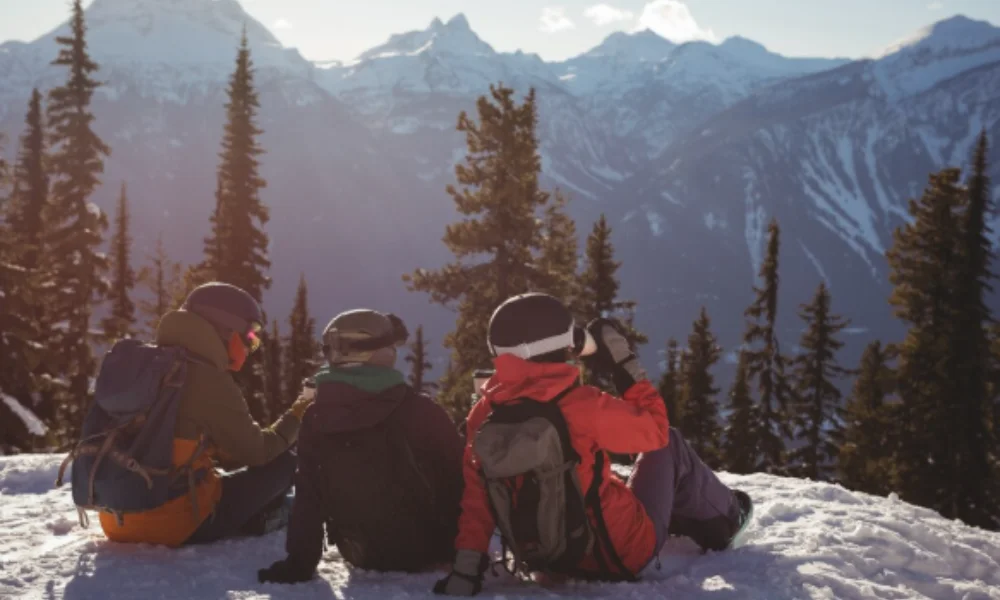 Three people in winter gear sit on a snowy hill-colorado places to visit