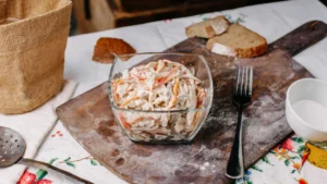 A glass bowl filled with creamy salad, including sliced carrots and peppers