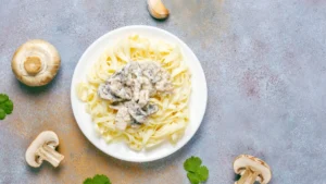 A plate of creamy mushroom pasta on a textured surface