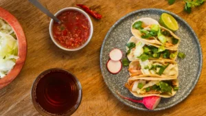 A plate with three tacos filled with lettuce and meat