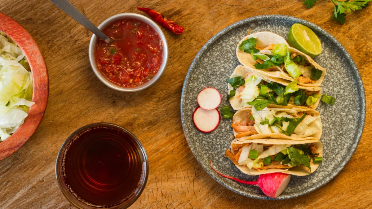 A plate with three tacos filled with lettuce and meat