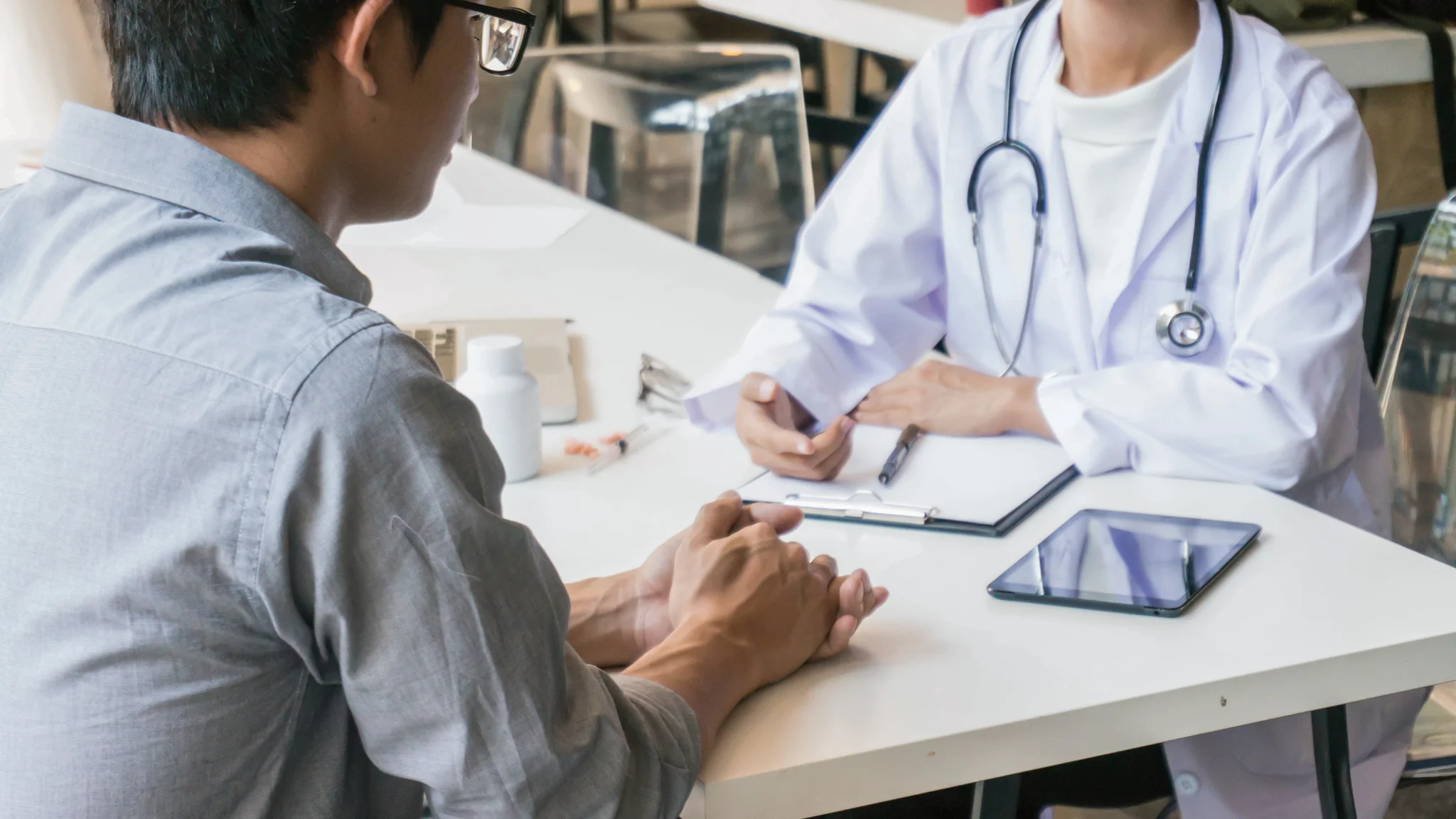 A doctor converses with a patient in a bright, welcoming office setting.