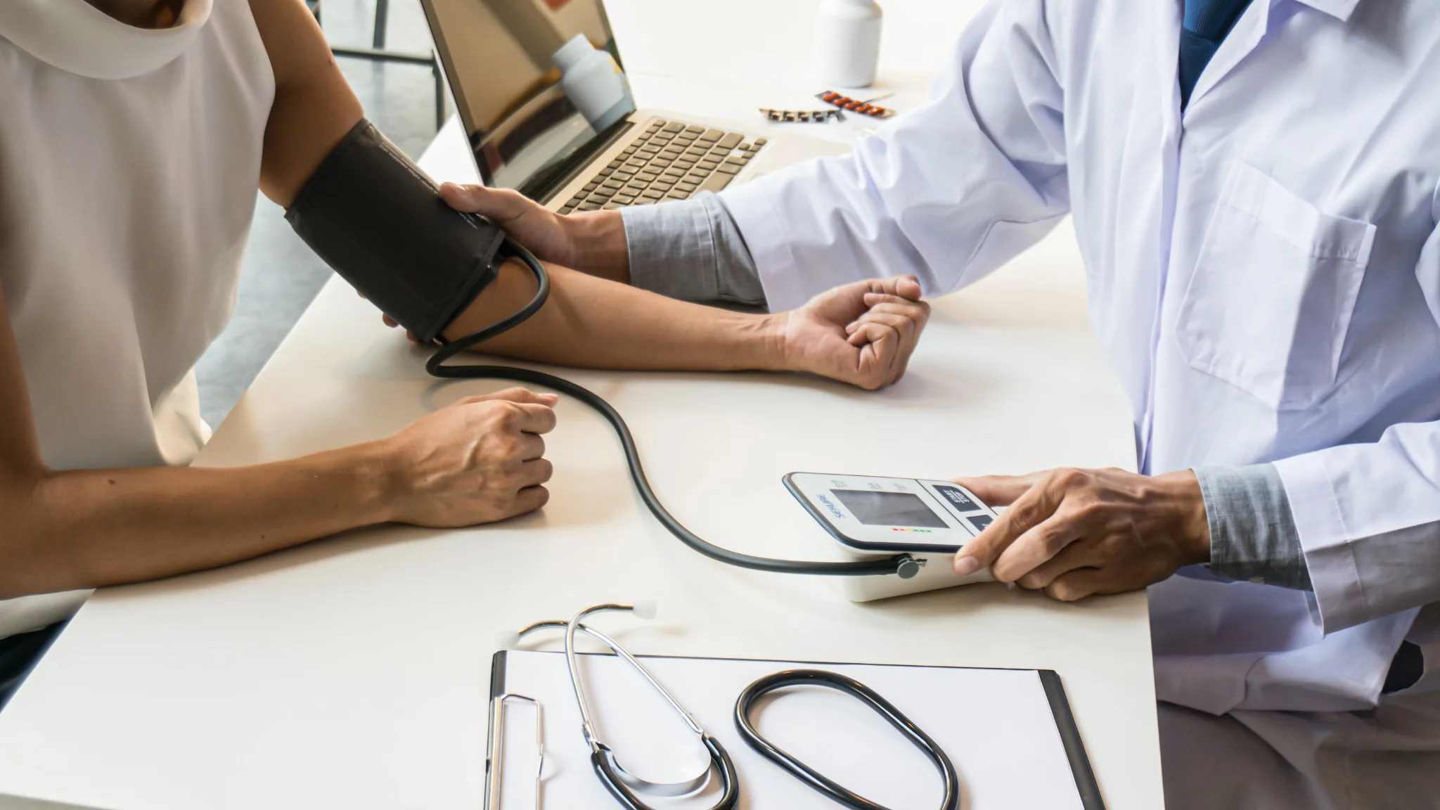 A doctor measures a patient's blood pressure using a sphygmomanometer in a clinical setting.