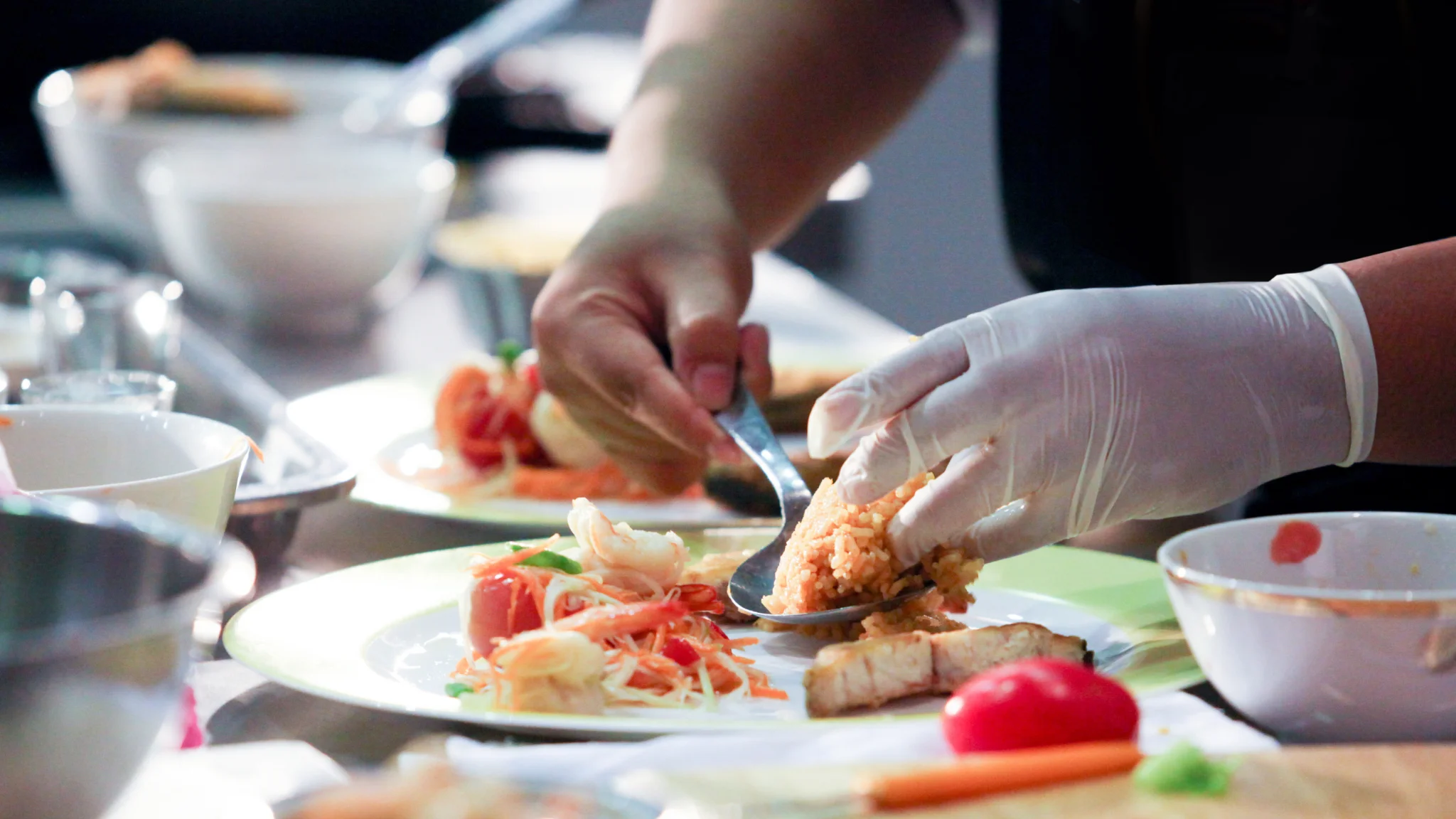 A person in a kitchen skillfully arranging food on a plate, surrounded by fresh ingredients and cooking utensils.